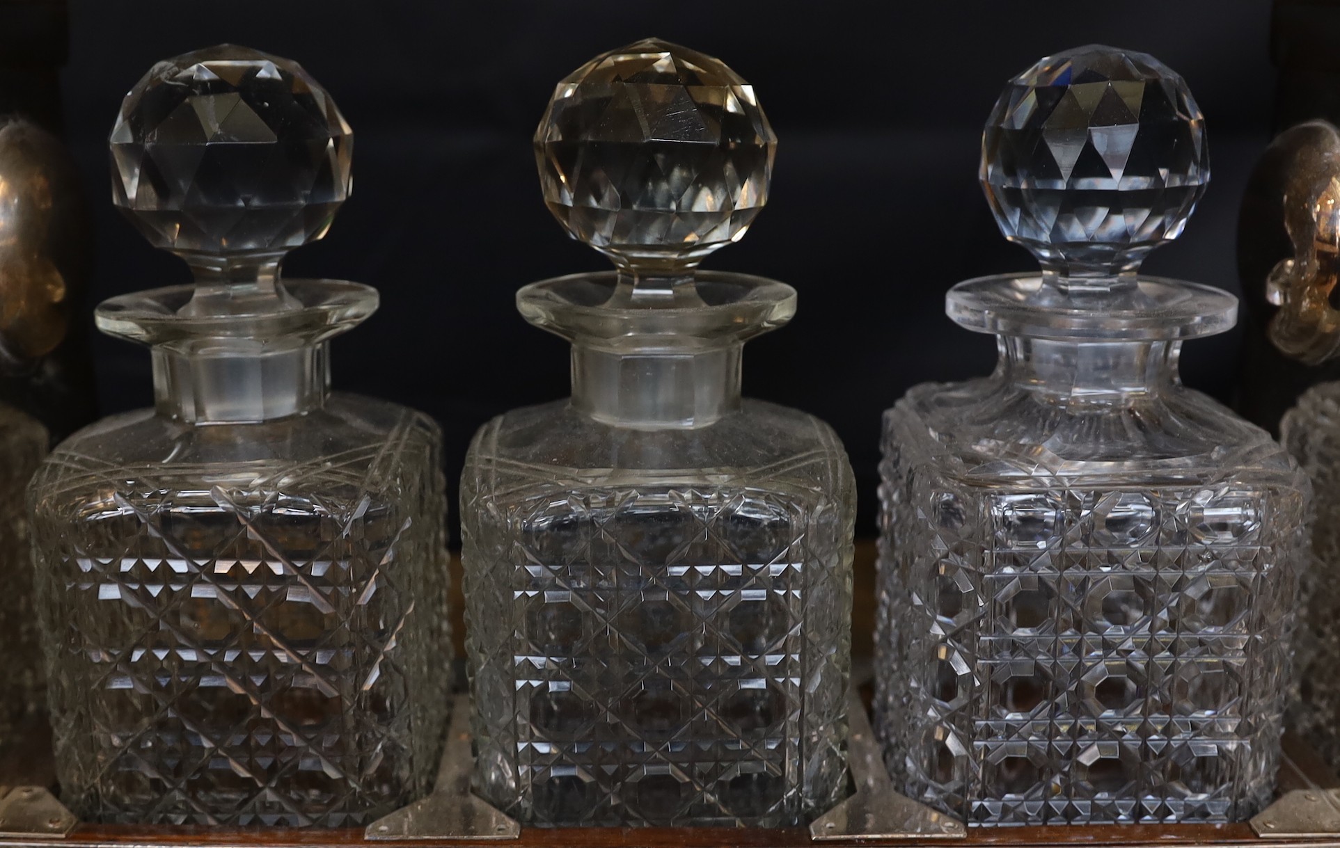 An Edwardian silver plated mounted oak tantalus fitted with three cut glass decanters, width 36cm